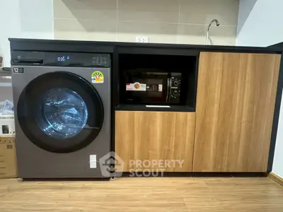 Modern laundry area with washing machine and microwave in sleek cabinetry.