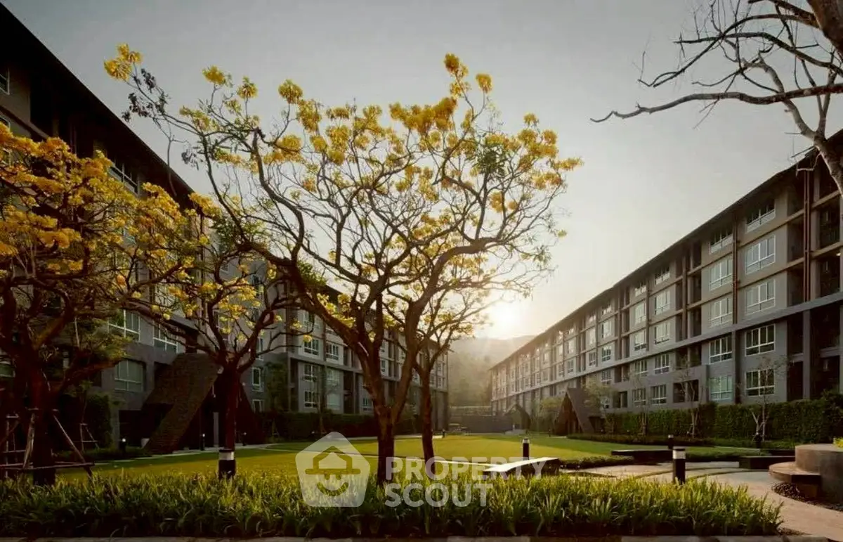 Modern apartment complex with lush garden and blooming trees at sunrise.