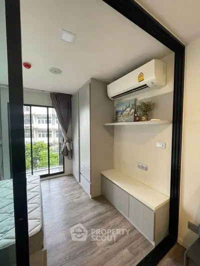 Modern bedroom with air conditioning and balcony view, featuring sleek design and natural light.