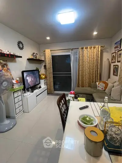 Cozy living room with modern decor, featuring a comfortable sofa, entertainment unit, and dining area.