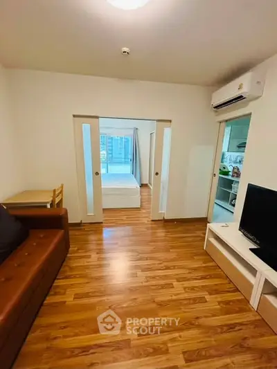 Modern apartment interior with wooden flooring, open layout, and cozy furnishings.