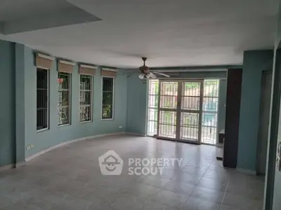 Spacious living room with large windows and ceiling fan in modern apartment