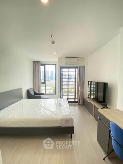 Modern bedroom with city view, featuring a large window, sleek furniture, and a comfortable bed.