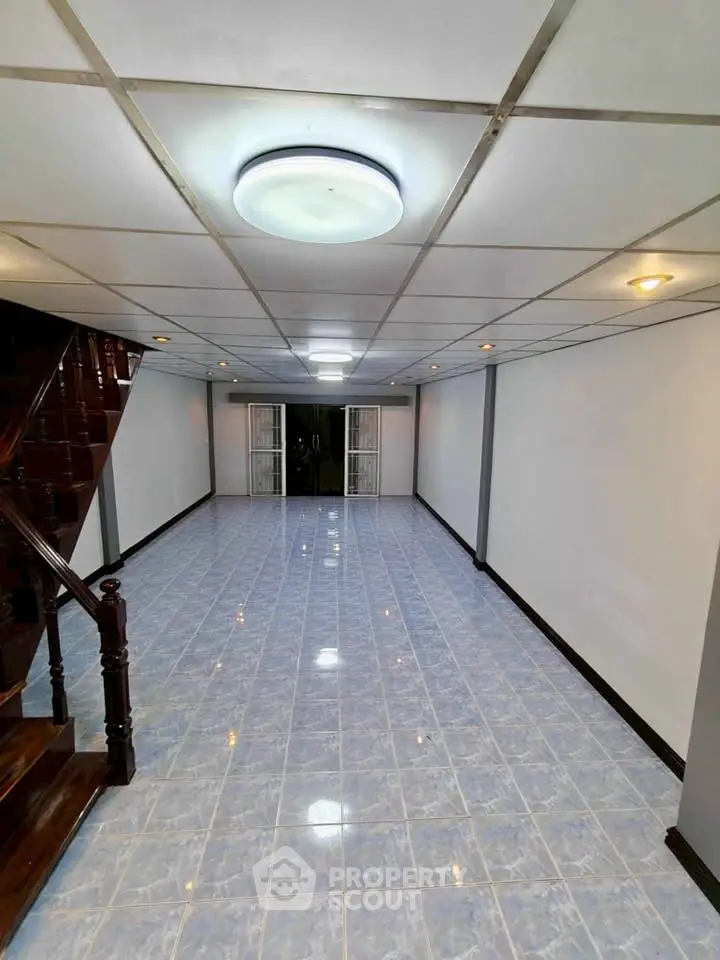 Spacious tiled interior with modern lighting and staircase, perfect for versatile living space.