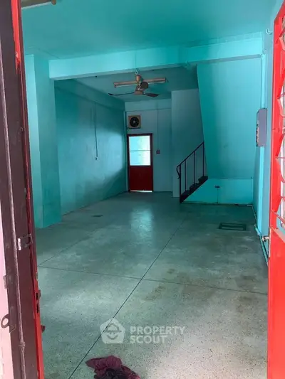 Spacious interior with vibrant blue walls and red accents, featuring a ceiling fan and staircase.