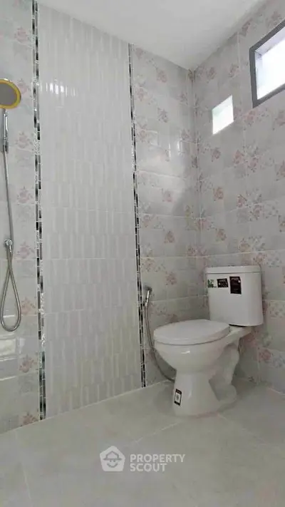 Modern bathroom with floral tiles and shower in a bright, airy space.