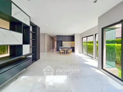 Spacious modern living room with marble flooring and large windows overlooking greenery.