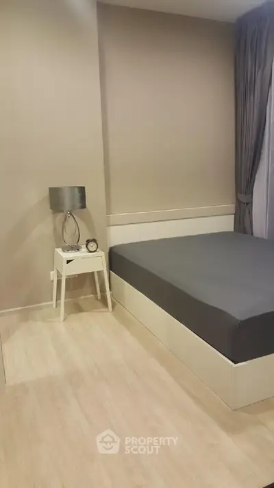 Modern bedroom with minimalist design featuring a sleek bed and stylish lamp.