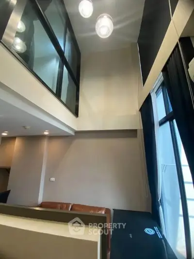 Modern loft-style living room with high ceilings and large windows