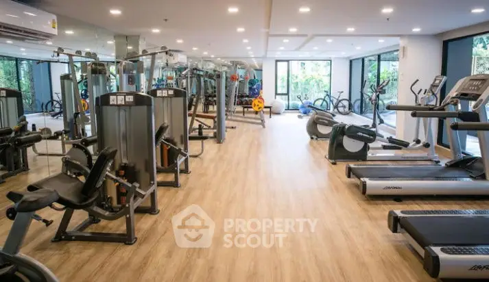 Spacious modern gym with state-of-the-art equipment and large windows for natural light.
