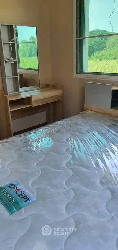 Cozy bedroom with a large window offering a scenic view, featuring a wooden vanity and a comfortable bed.