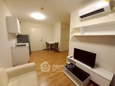 Modern living room with sleek furniture and open kitchen layout, featuring air conditioning and wooden flooring.