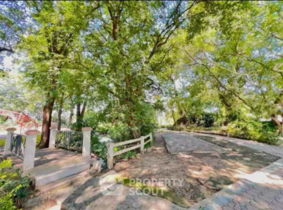 Serene garden pathway with lush greenery and trees, perfect for relaxation.