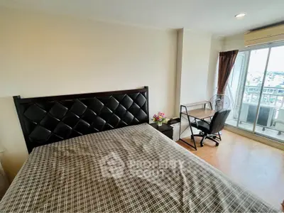 Spacious bedroom with balcony access and city view, featuring modern furniture and ample natural light.