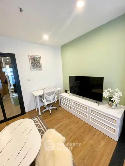 Modern living room with stylish decor and flat-screen TV, featuring a cozy workspace and elegant furnishings.