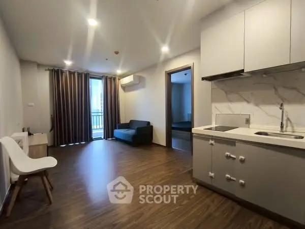 Modern open-plan living room with sleek kitchen and balcony access.