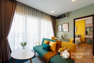 Charming and vibrant living room with a plush green sofa, accented by mustard yellow pillows, seamlessly connects to a cozy bedroom, bathed in natural light from floor-to-ceiling windows, offering a harmonious blend of comfort and style.