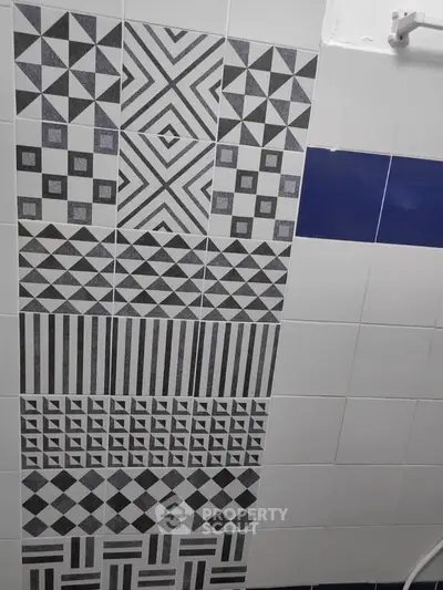 Stylish bathroom wall with geometric patterned tiles in monochrome design.