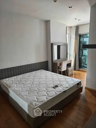 Spacious bedroom with modern decor and large window for natural light.