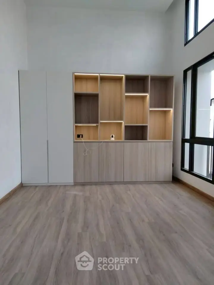 Spacious modern living room with built-in wooden shelves and large windows