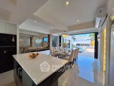 Luxurious open-plan kitchen and dining area with pool view, featuring modern design and elegant lighting.