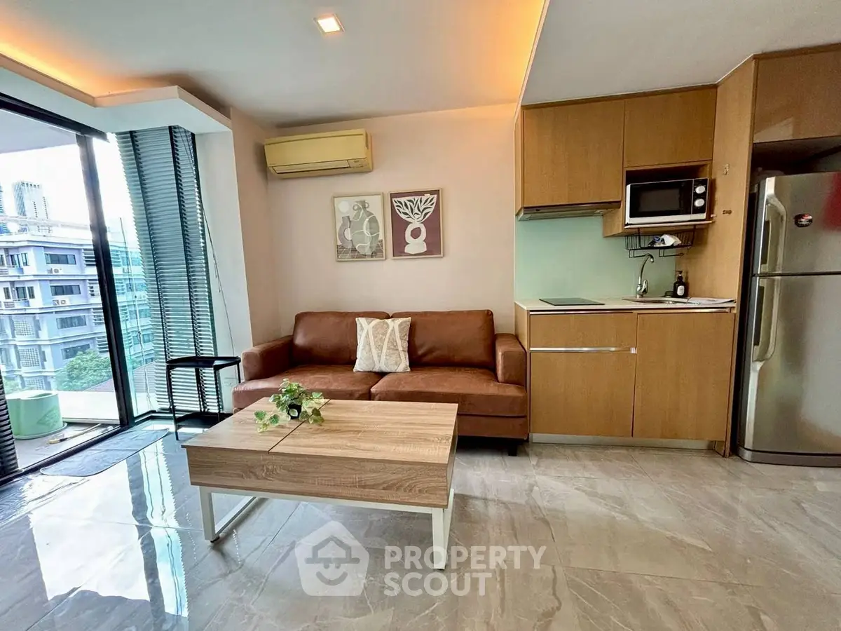 Modern living room with open kitchen, featuring sleek furniture and large windows with city view.