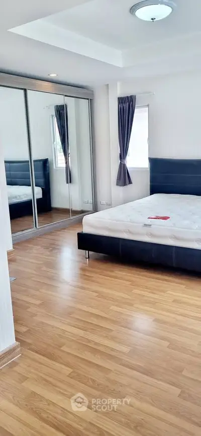 Spacious bedroom with mirrored closet and wooden flooring