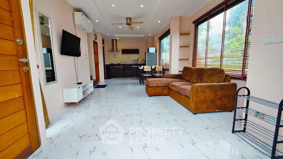 Spacious living room with modern kitchen and large windows for natural light.