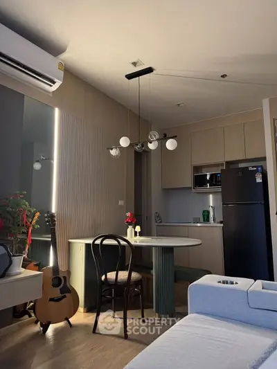 Modern living room with stylish decor, featuring a guitar, dining area, and sleek kitchen appliances.