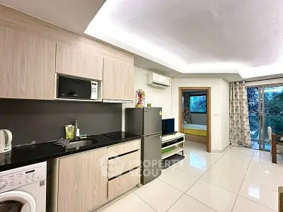 Modern open-layout kitchen with sleek appliances and view into cozy living area and bedroom.