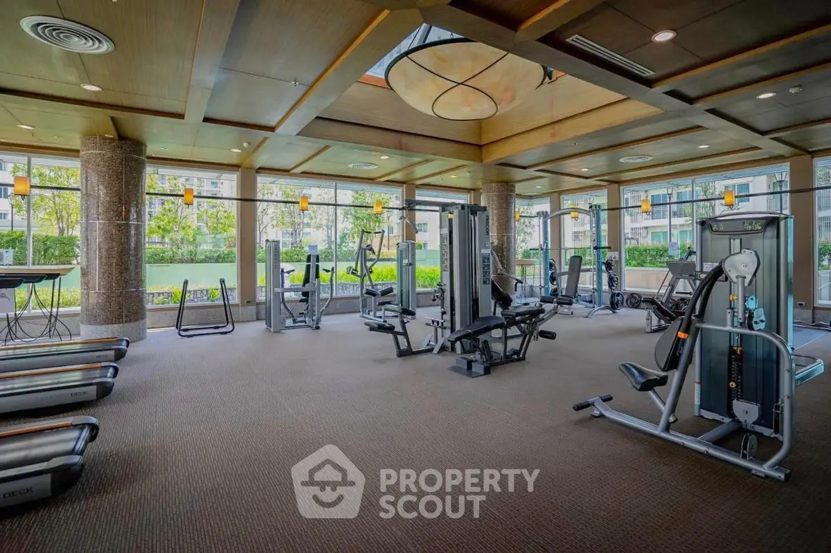 Spacious modern gym with state-of-the-art equipment and large windows offering garden views.