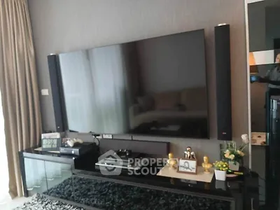 Modern living room with large flat-screen TV and sleek black entertainment unit.