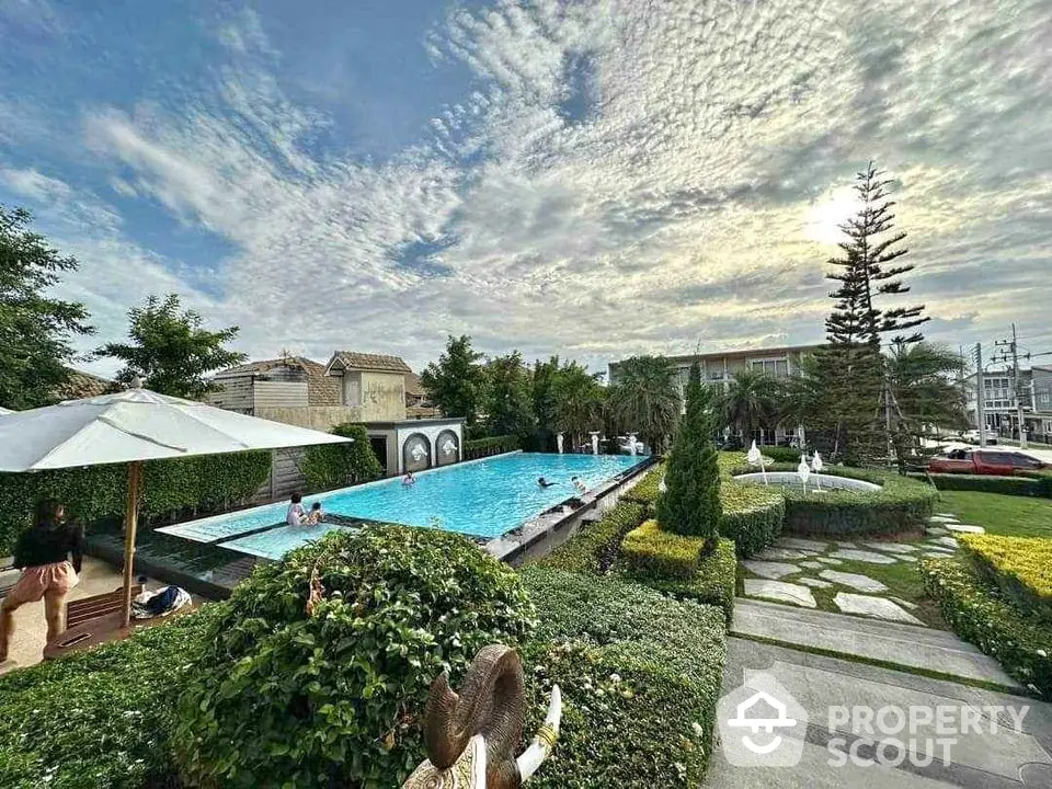 Luxurious residential pool with lush garden and sunbathing area, perfect for relaxation and leisure.