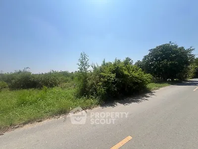 Expansive land plot with lush greenery and clear blue sky, ideal for development.