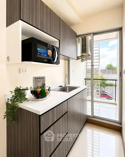 Modern kitchen with sleek cabinetry and balcony access, featuring a built-in microwave and stylish decor.