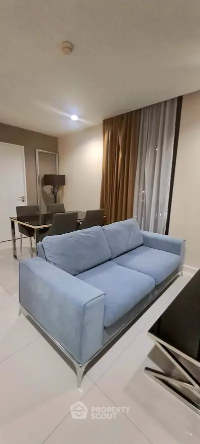 Modern living room with stylish blue sofa and elegant dining area