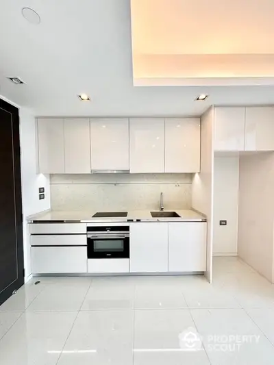 Modern minimalist kitchen with sleek white cabinetry and integrated appliances.