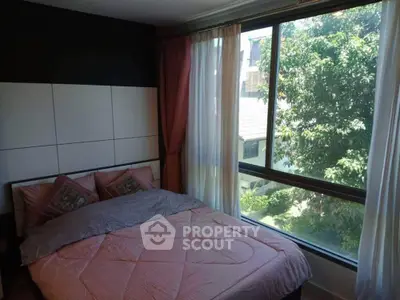 Cozy bedroom with large window offering ample natural light and a serene view, complemented by elegant drapery and a modern headboard.
