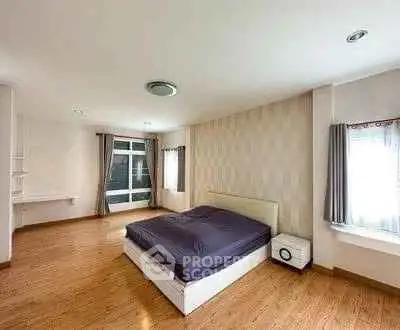 Spacious modern bedroom with wooden flooring and large windows