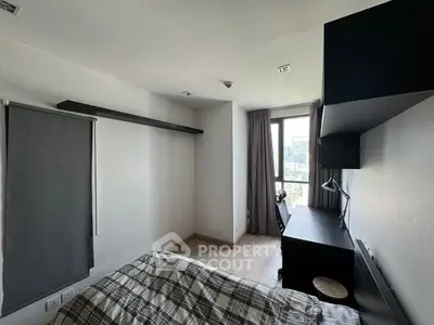 Modern bedroom with large windows offering ample natural light, featuring a cozy bed, sleek wall-mounted TV, and elegant dark curtains.