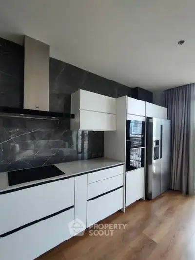 Modern kitchen with sleek white cabinets and stainless steel appliances in a stylish apartment.