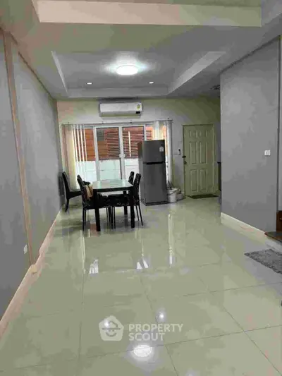 Spacious dining area with modern decor and natural light, featuring sleek furniture and a contemporary fridge.
