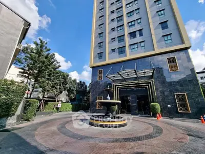 Modern high-rise building entrance with elegant fountain and landscaped surroundings.