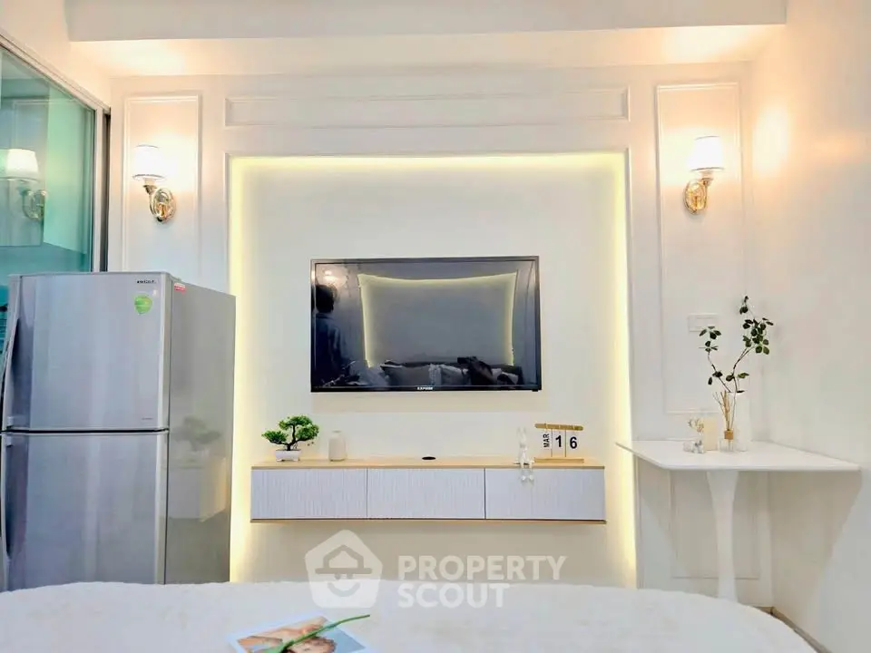 Modern living room with sleek TV setup and stainless steel fridge, perfect for contemporary urban living.