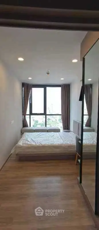 Modern bedroom with large window offering city view, featuring sleek design and ample natural light.