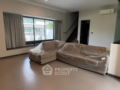 Spacious living room with modern L-shaped sofa and large window, perfect for natural light.