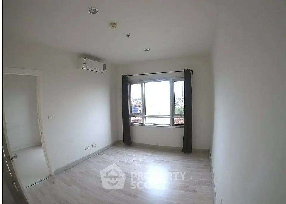 Spacious empty bedroom with large window and air conditioning, ready for customization.