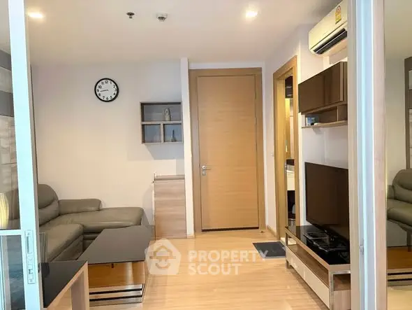 Modern living room with sleek furniture and wall-mounted TV in a cozy apartment setting.
