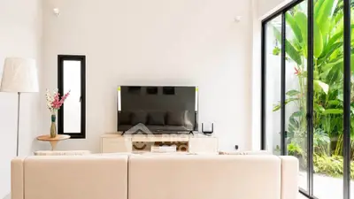 Modern living room with large glass doors opening to lush garden, featuring sleek furniture and a flat-screen TV.