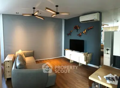 Modern living room with stylish decor and wooden flooring, featuring a comfortable sofa and wall-mounted TV.